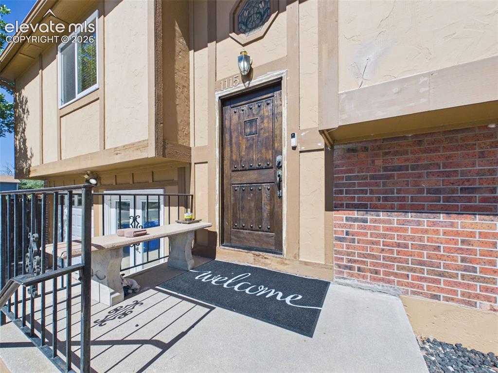 Image 3 of 50: Raised front entry with metal railing, distinctive wood-look entry door, an
