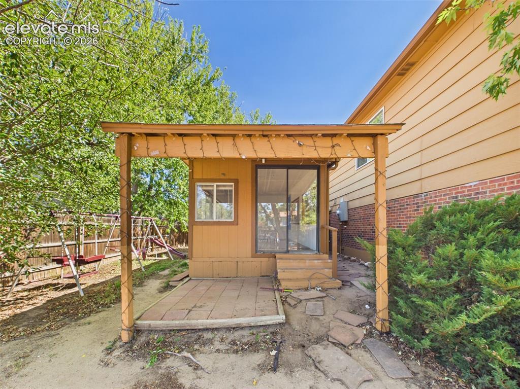 Image 39 of 50: Covered patio area extends alongside the enclosed sunroom, offering a shelt