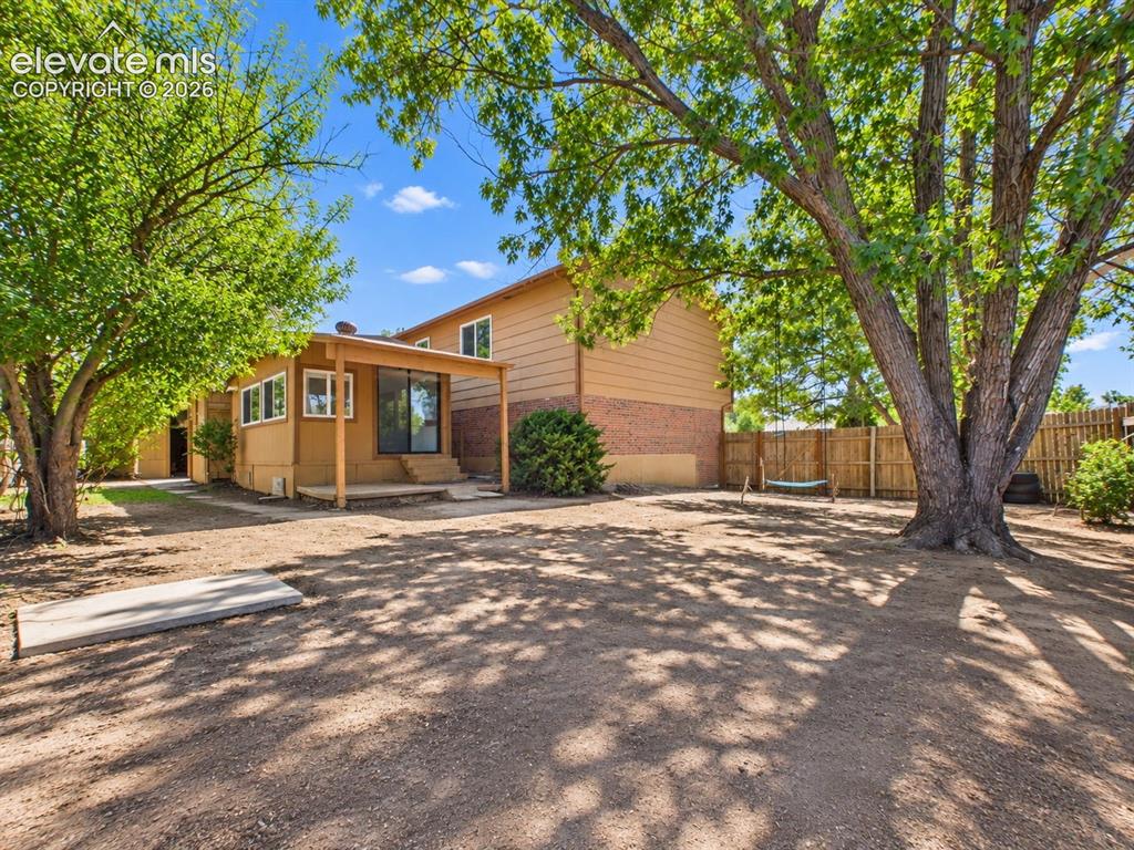 Image 42 of 50: Spacious fenced backyard is shaded by mature trees and includes an outdoor 