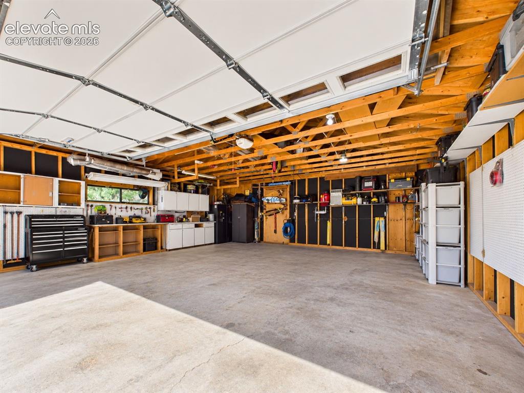 Image 47 of 50: Spacious garage features extensive wall storage, cabinetry, work surfaces, 