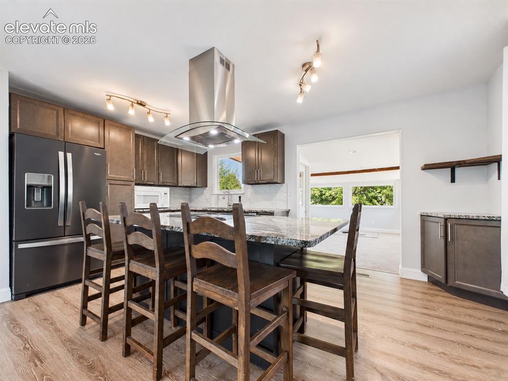 Image 9 of 50: Another angle highlights the generous island seating, abundant cabinetry, a