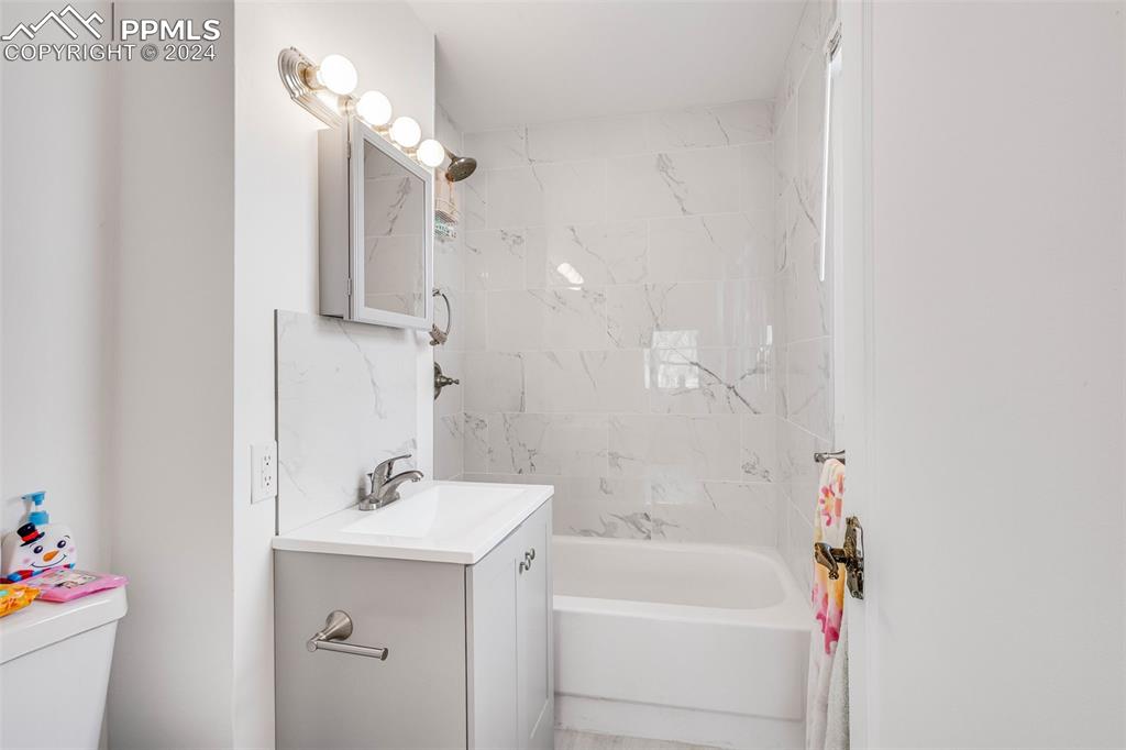 Image 10 of 29: Full bathroom with oversized vanity, toilet, and tiled shower / bath