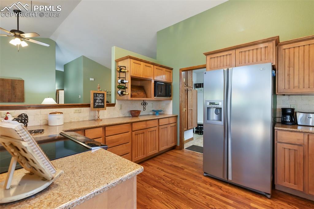 Image 17 of 43: Kitchen featuring stainless steel fridge with ice dispenser, lofted ceiling