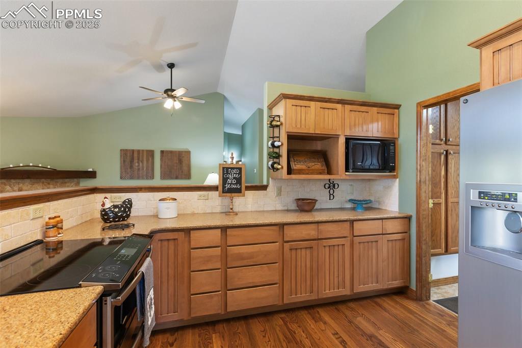 Image 18 of 43: Kitchen with appliances with stainless steel finishes, vaulted ceiling, tas
