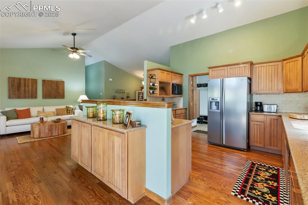 Image 19 of 43: Kitchen with stainless steel fridge, open floor plan, light wood-type floor