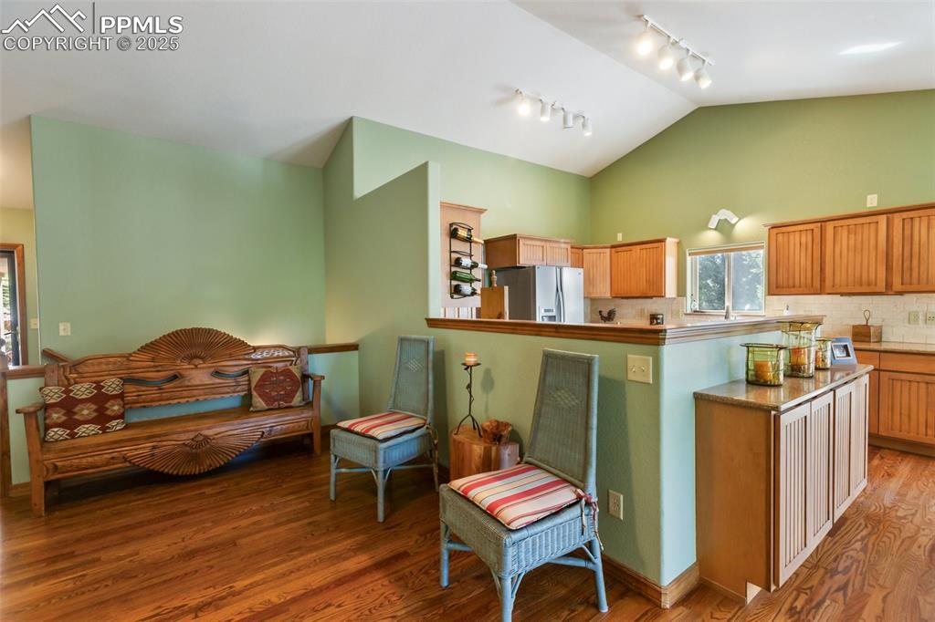 Image 20 of 43: Kitchen with rail lighting, white refrigerator with ice dispenser, wood fin