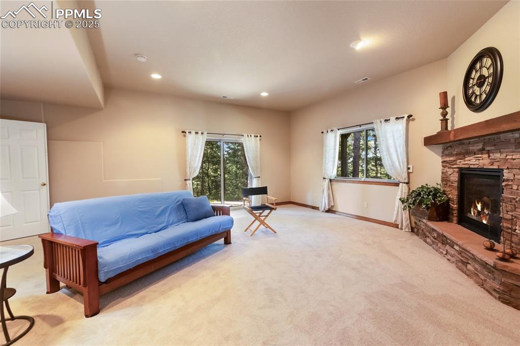 Image 22 of 43: Carpeted living area featuring a stone fireplace and recessed lighting