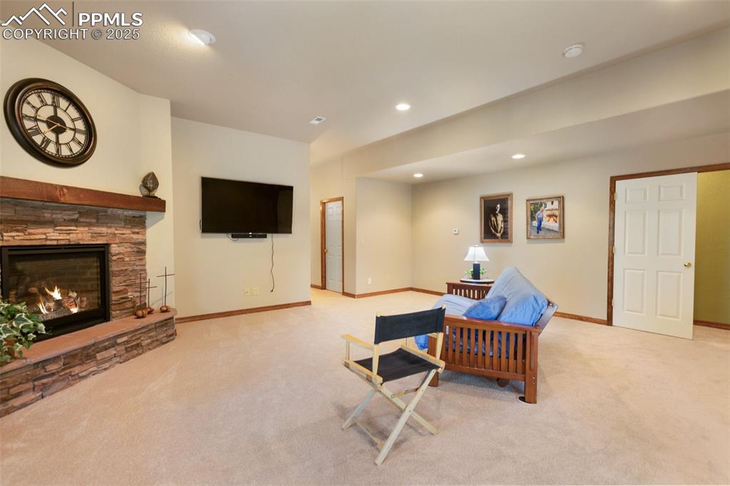 Image 24 of 43: Carpeted living room with recessed lighting and a stone fireplace