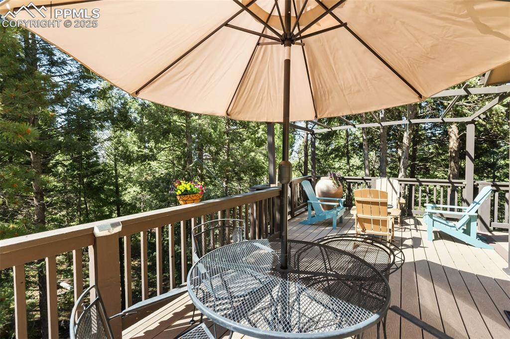 Image 26 of 43: Wooden terrace featuring outdoor dining area and view of scattered trees