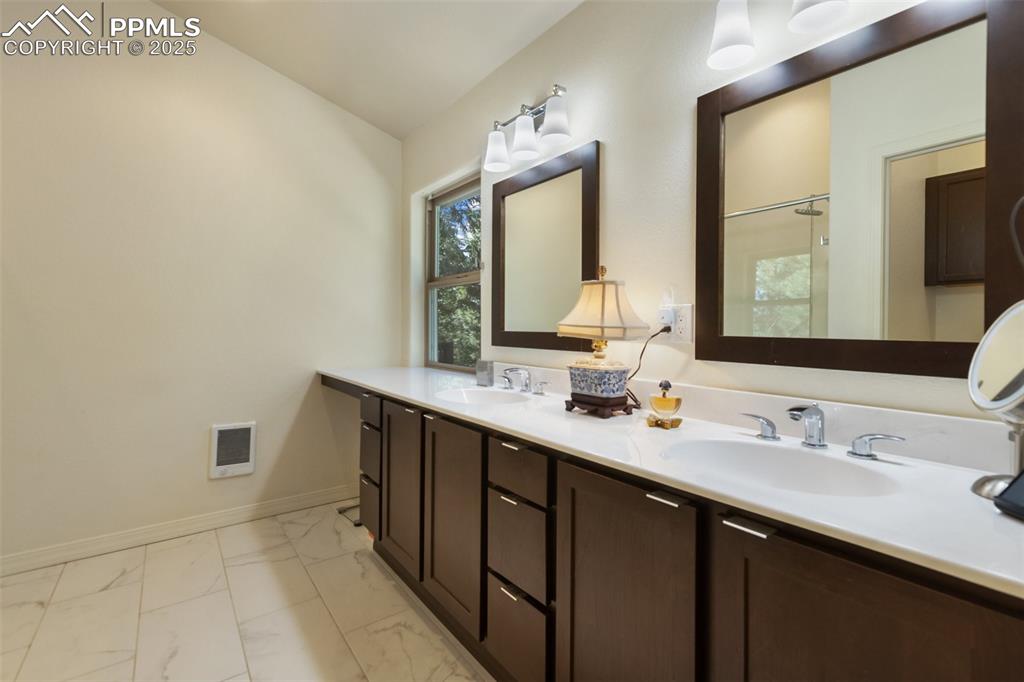 Image 31 of 43: Full bathroom featuring marble look tile flooring, double vanity, and a sho