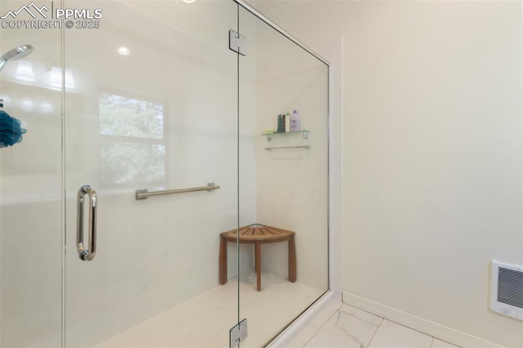 Image 32 of 43: Bathroom with a shower stall and marble look tiles