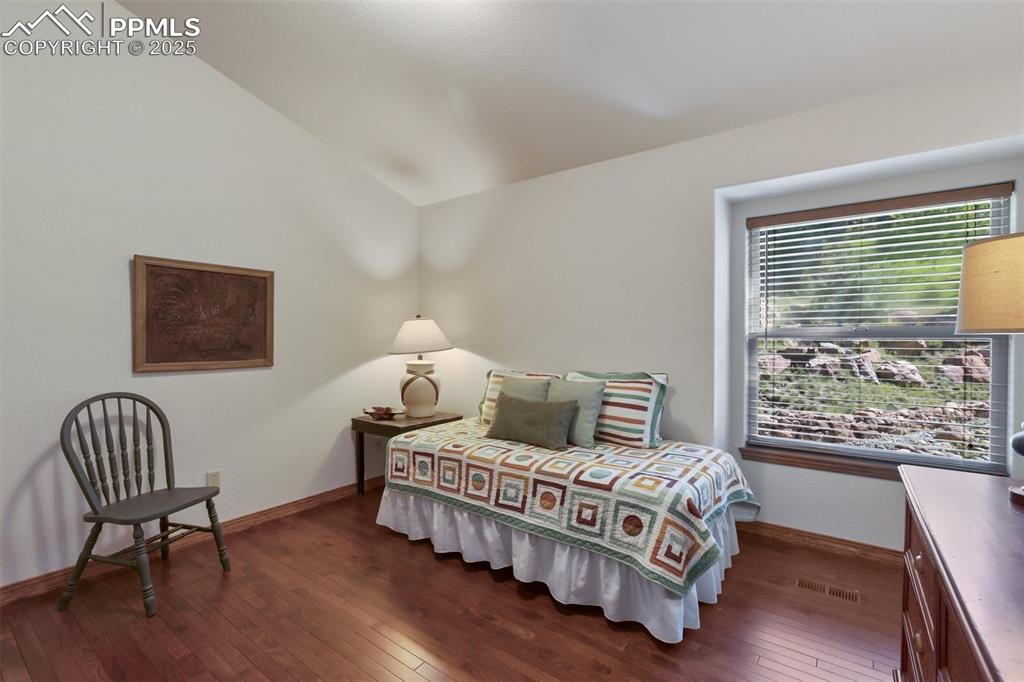 Image 38 of 43: Bedroom with dark wood-style flooring and vaulted ceiling