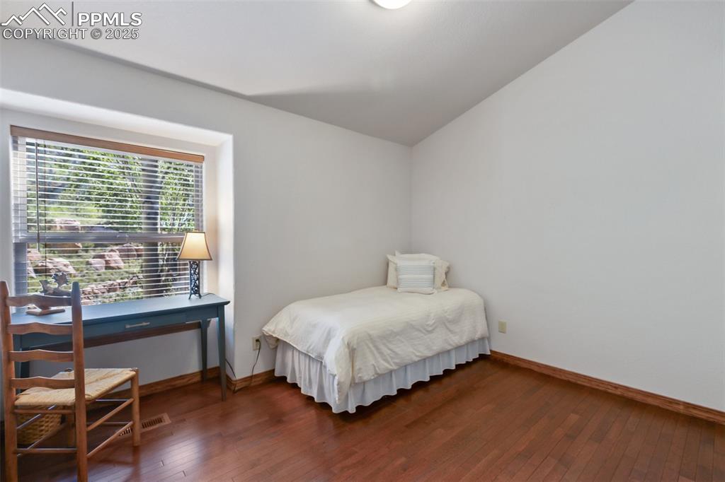 Image 40 of 43: Bedroom with dark wood finished floors and vaulted ceiling