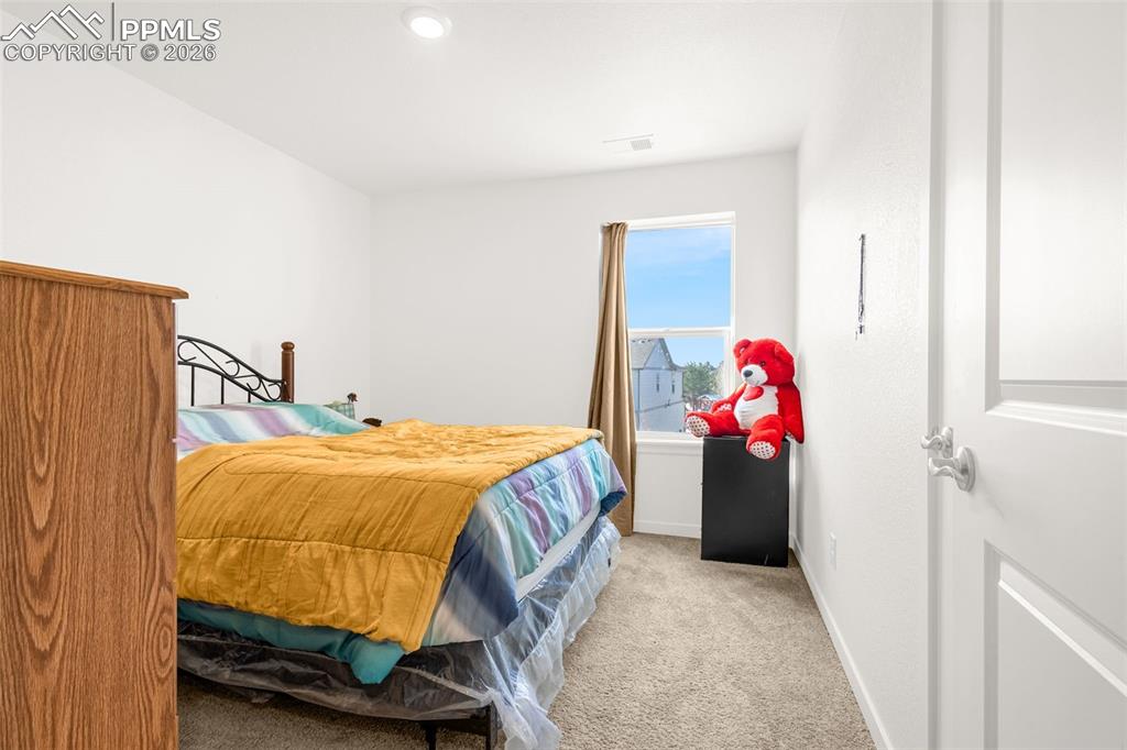 Image 11 of 27: Bedroom with visible vents, light colored carpet, and baseboards
