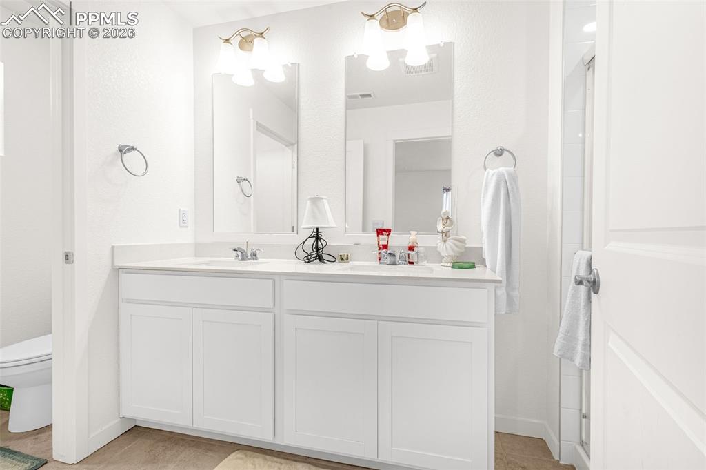 Image 14 of 27: Bathroom featuring double vanity, visible vents, a sink, and toilet