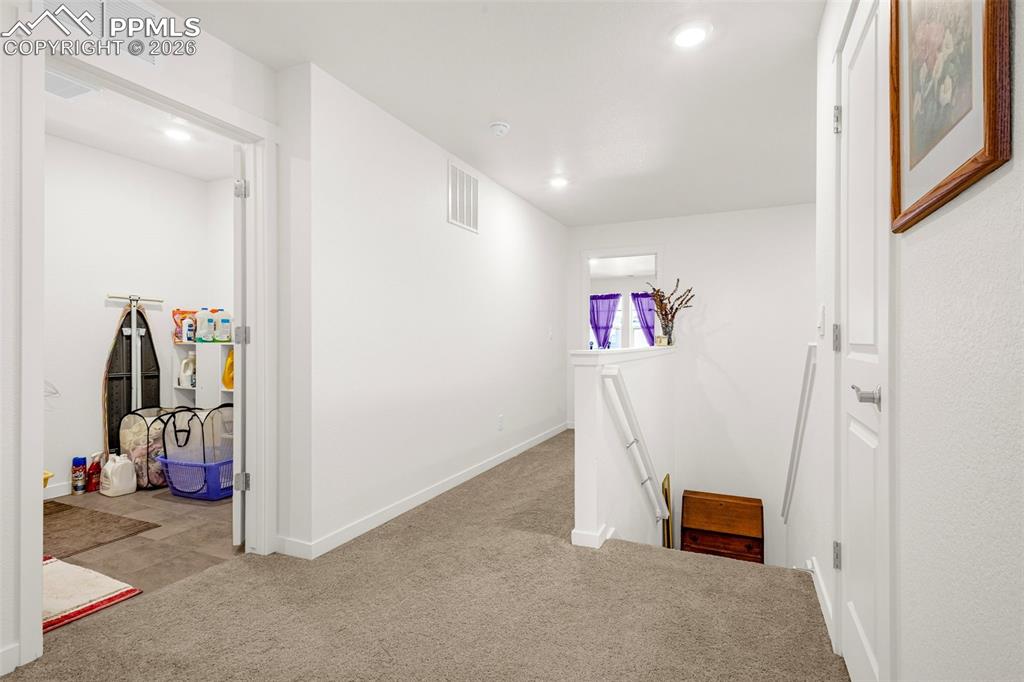 Image 17 of 27: Hall with visible vents, an upstairs landing, carpet, and recessed lighting