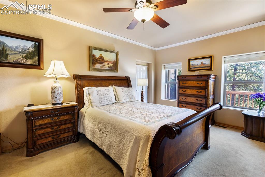Image 23 of 47: The main bedroom with light carpet, crown molding, and ceiling fan.
