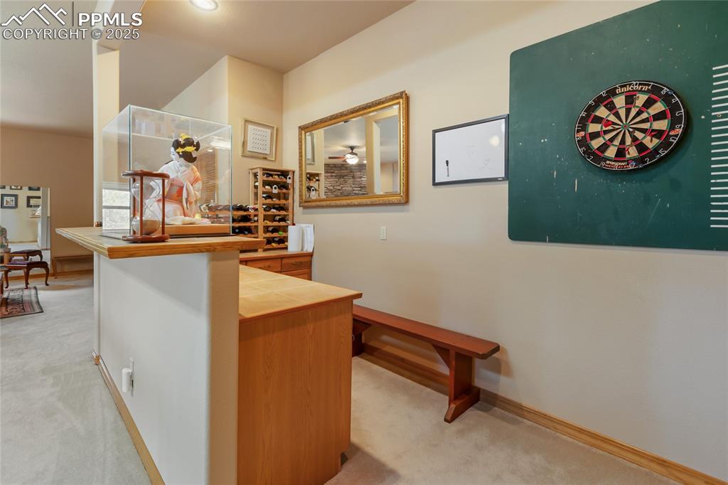 Image 41 of 47: Dry bar featuring tile counters and brown cabinets.