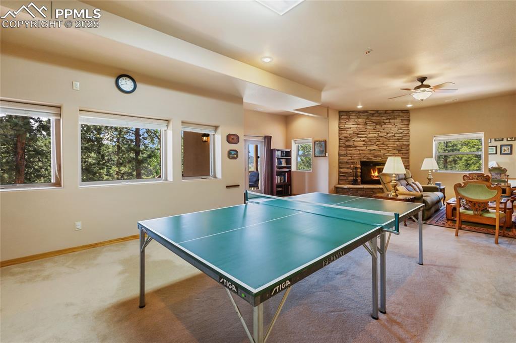 Image 42 of 47: Rec room featuring carpet, a fireplace, a ceiling fan, and recessed lightin