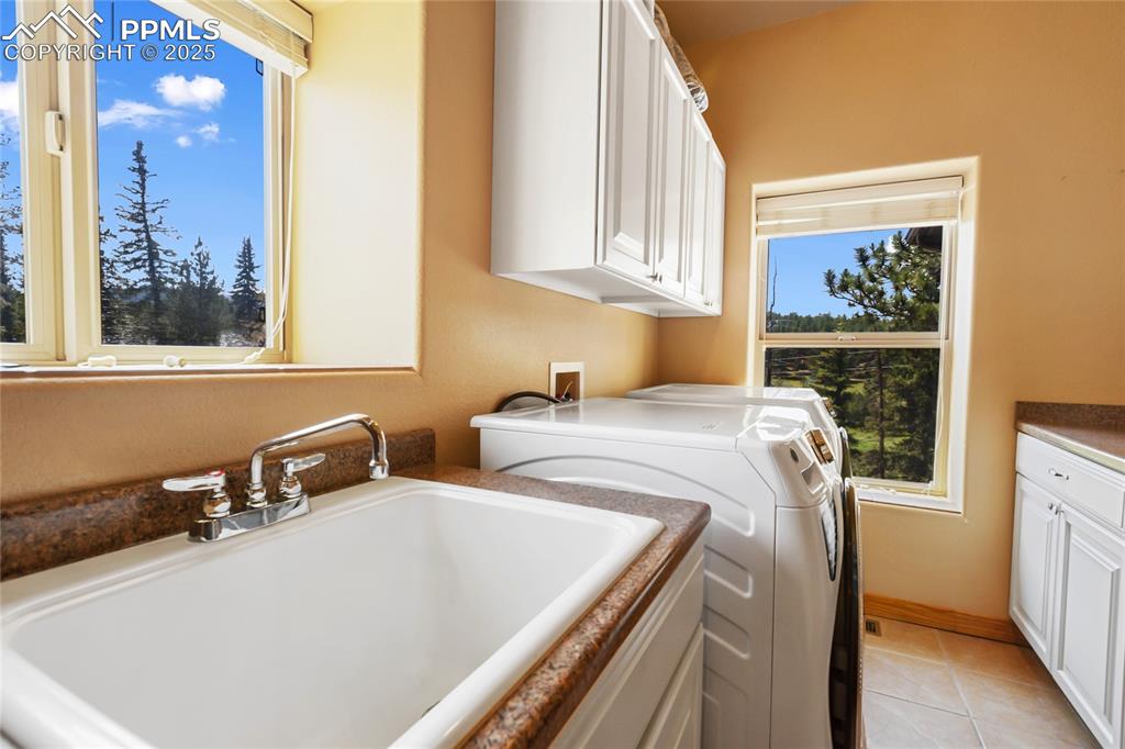 Image 43 of 47: The laundry area features a washing machine and dryer, light tiled flooring