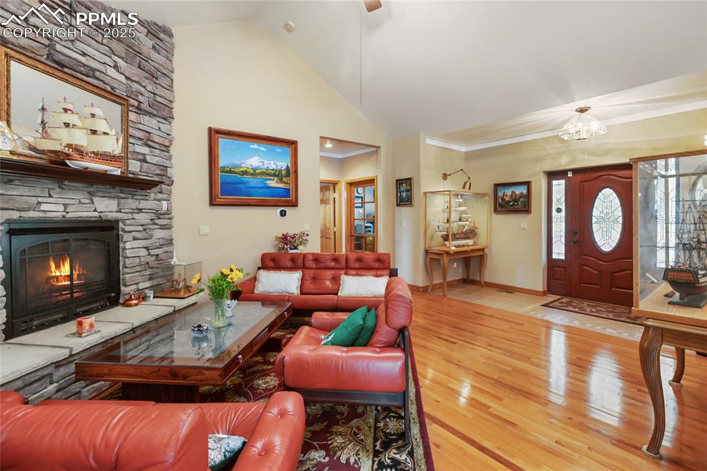 Image 8 of 47: Living room with high vaulted ceiling, wood finished floors, a fireplace, o