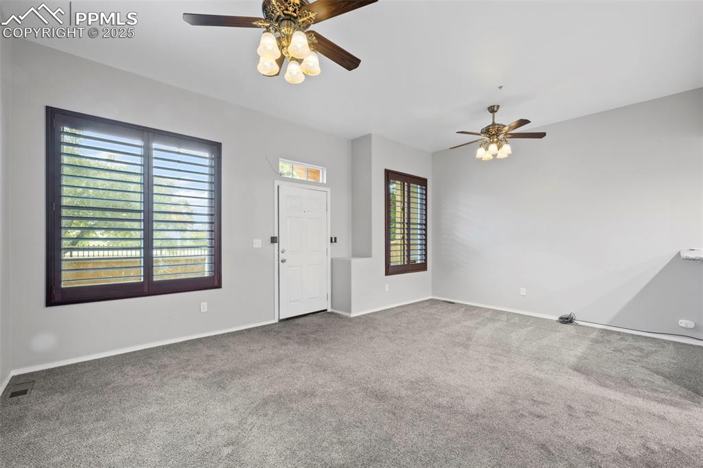 Image 10 of 23: Unfurnished living room featuring a ceiling fan, carpet floors, and baseboa