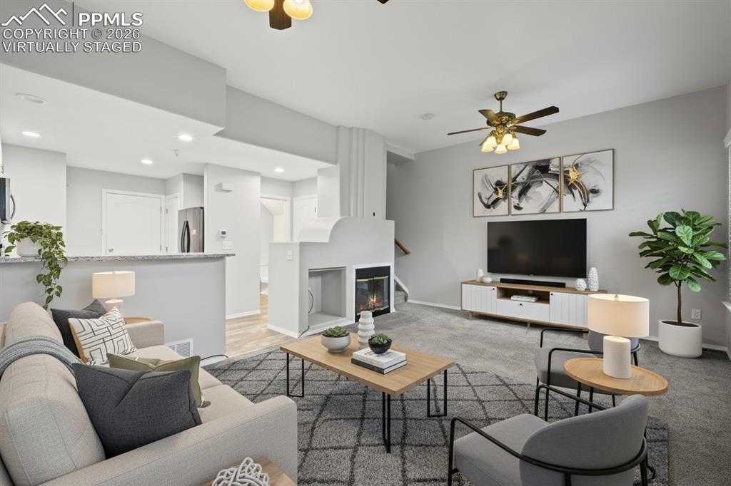 Image 10 of 33: Living room featuring custom window shutters, a ceiling fan, carpet floorin