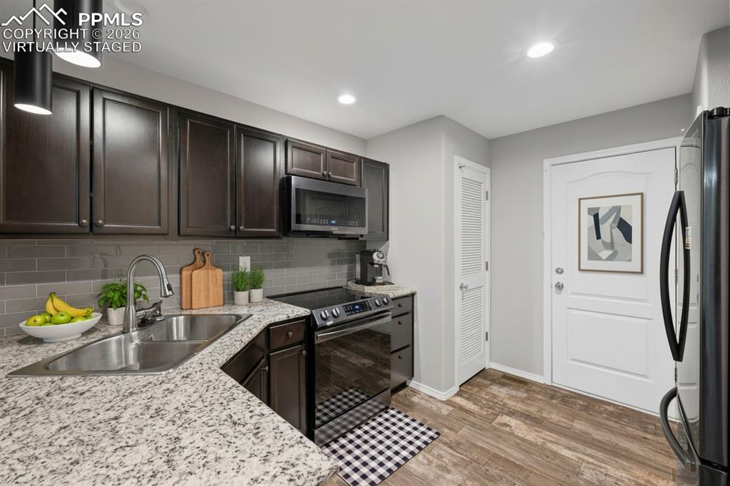 Image 11 of 33: Kitchen featuring stainless steel appliances, dark brown cabinetry, recesse