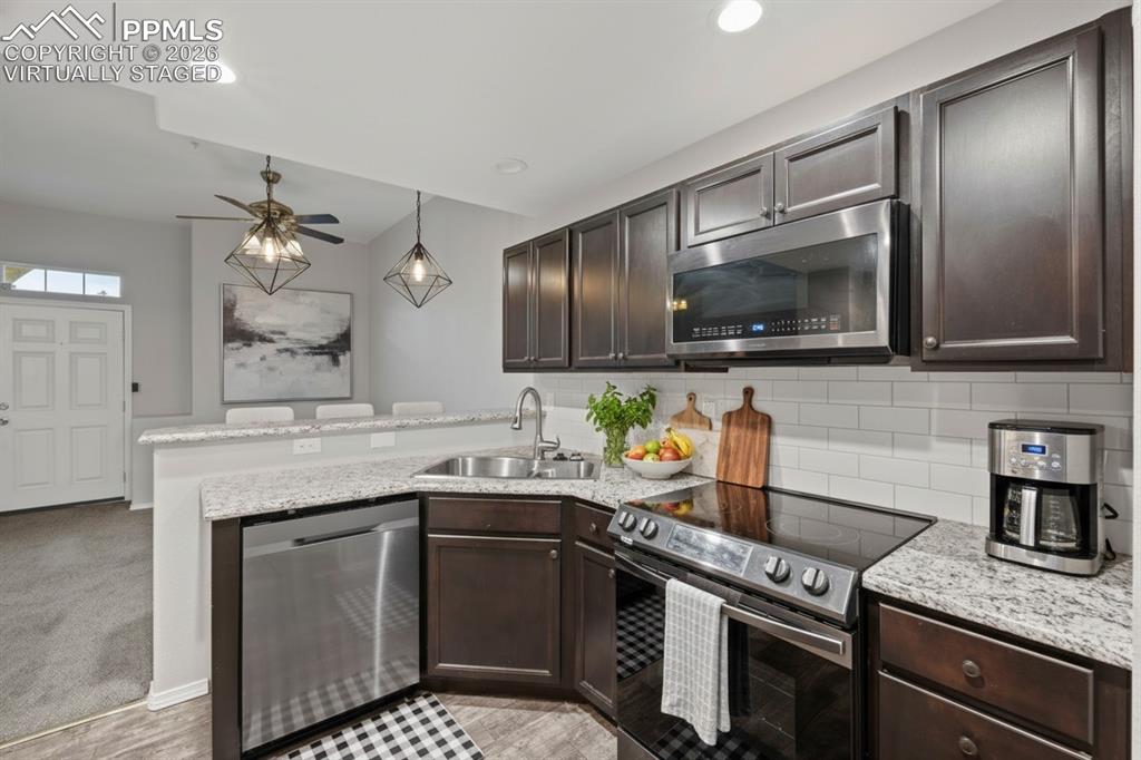 Image 12 of 33: Kitchen featuring stainless steel appliances, dark brown cabinetry, recesse