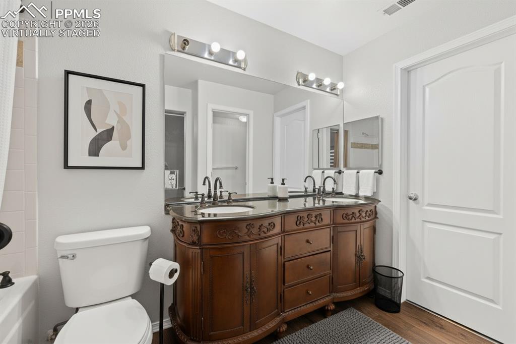 Image 18 of 33: Full bath with double vanity, shower / bathtub combination with curtain, an