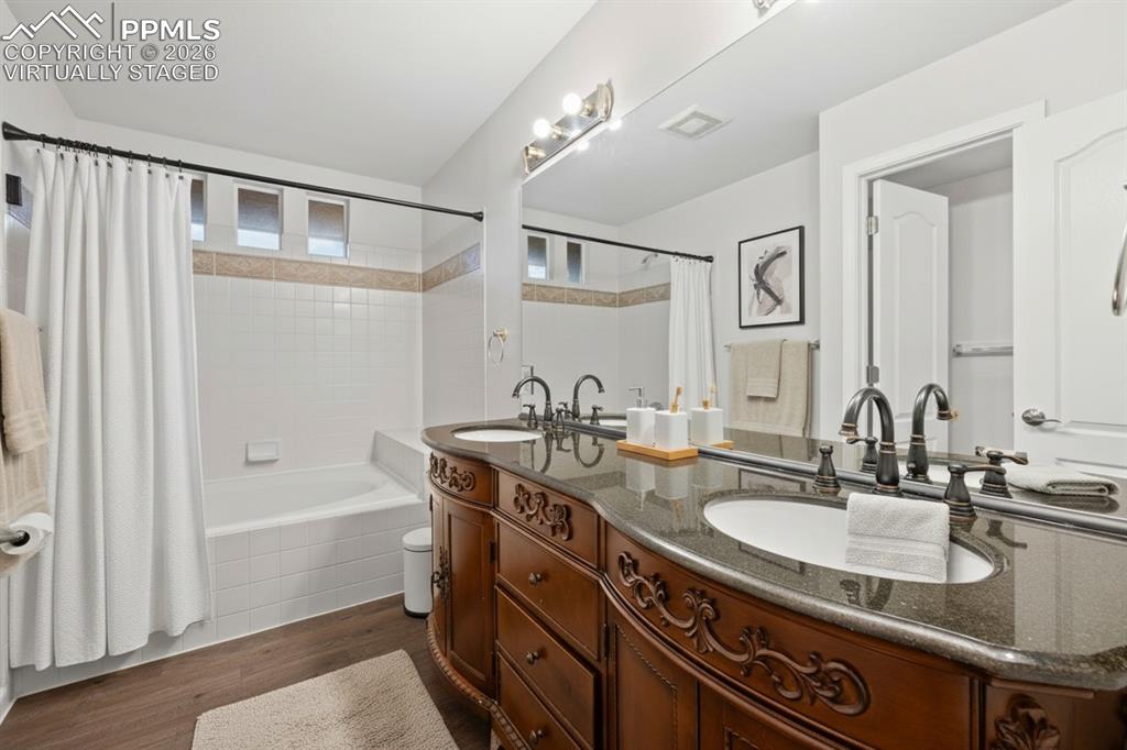 Image 19 of 33: Full bath with double vanity, shower / bathtub combination with curtain, an