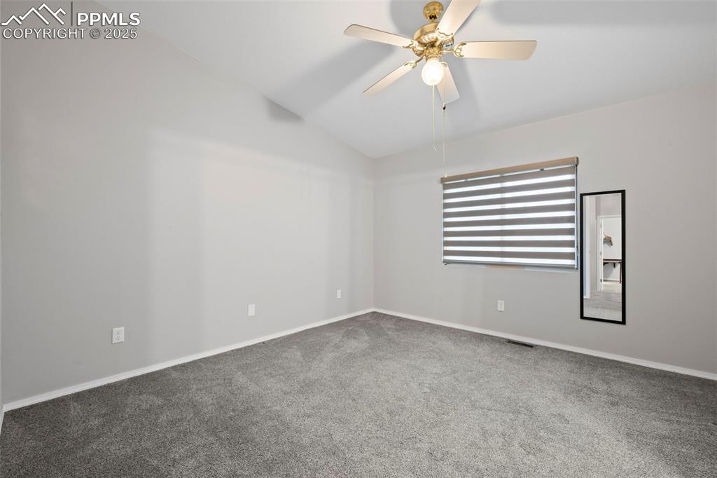 Image 20 of 23: Carpeted spare room featuring ceiling fan, vaulted ceiling, and baseboards