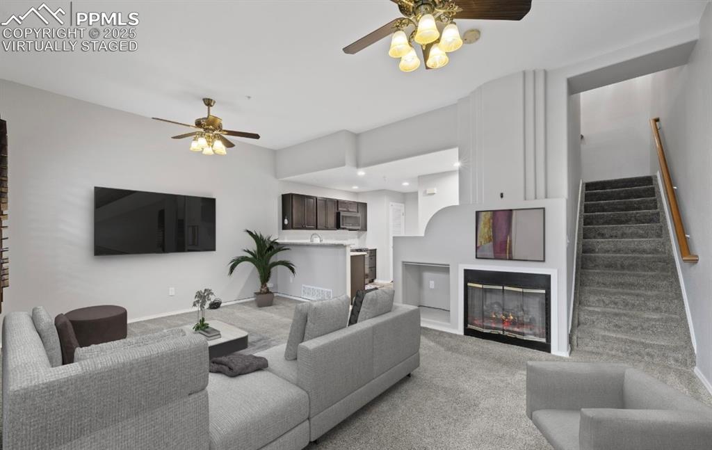 Image 8 of 23: Living room featuring a ceiling fan, carpet flooring, stairway, and a glass