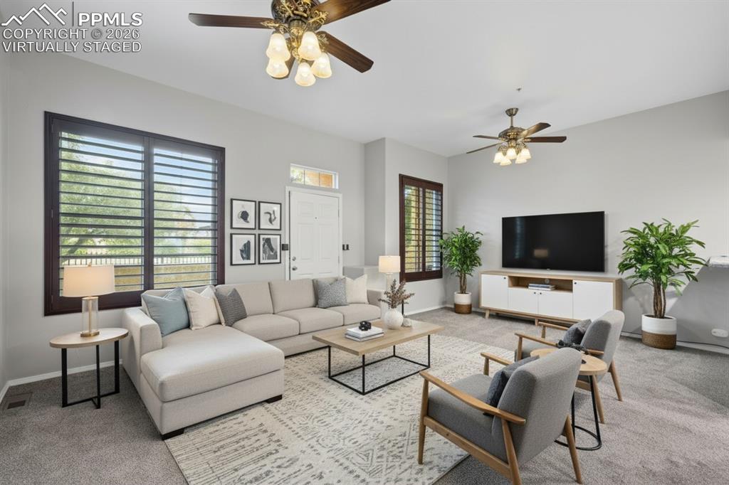 Image 9 of 33: Living room featuring custom window shutters, a ceiling fan, carpet floorin