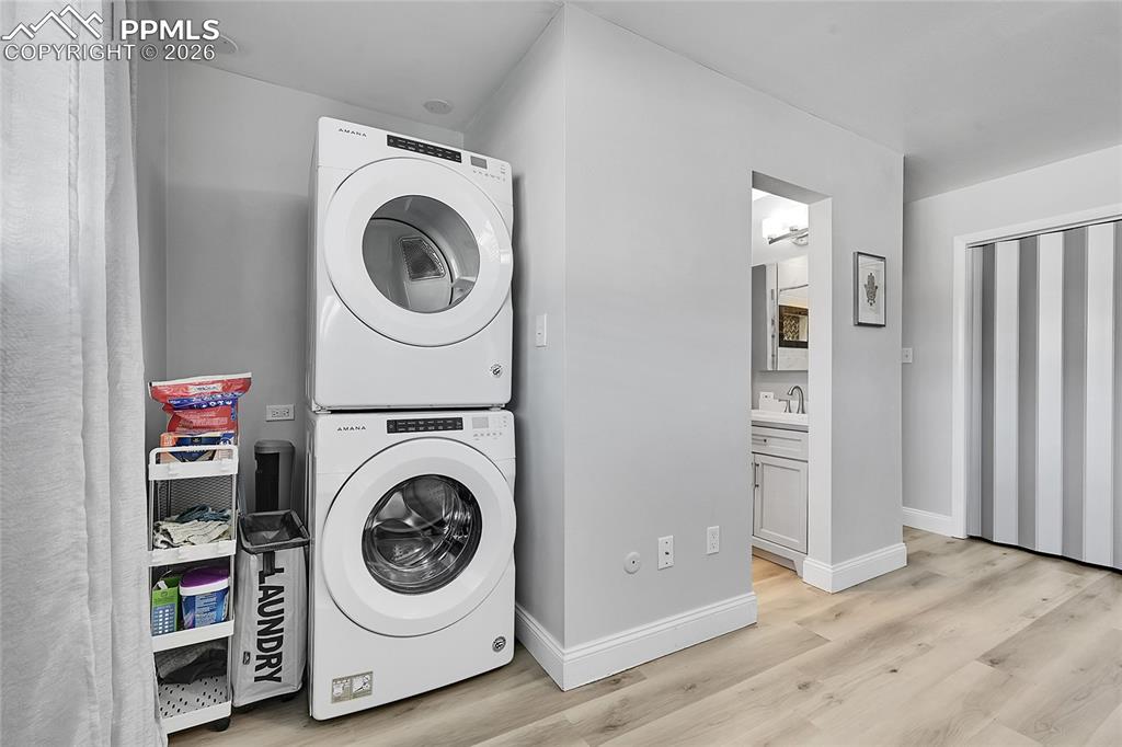 Image 15 of 42: Washroom with light hardwood / wood-style flooring, stacked washing maching