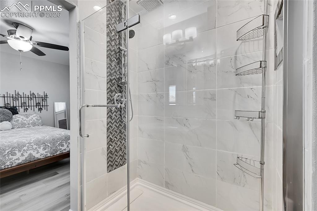 Image 16 of 42: Bathroom with hardwood / wood-style floors, ceiling fan, and an enclosed sh