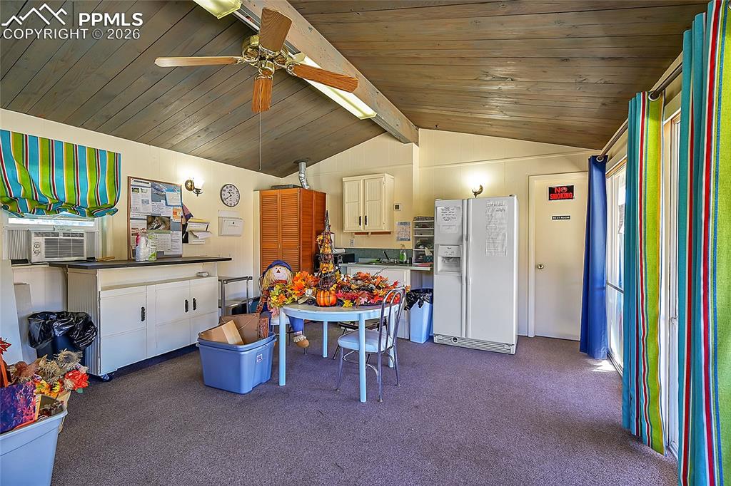 Image 29 of 42: Kitchen featuring dark colored carpet, lofted ceiling with beams, white ref