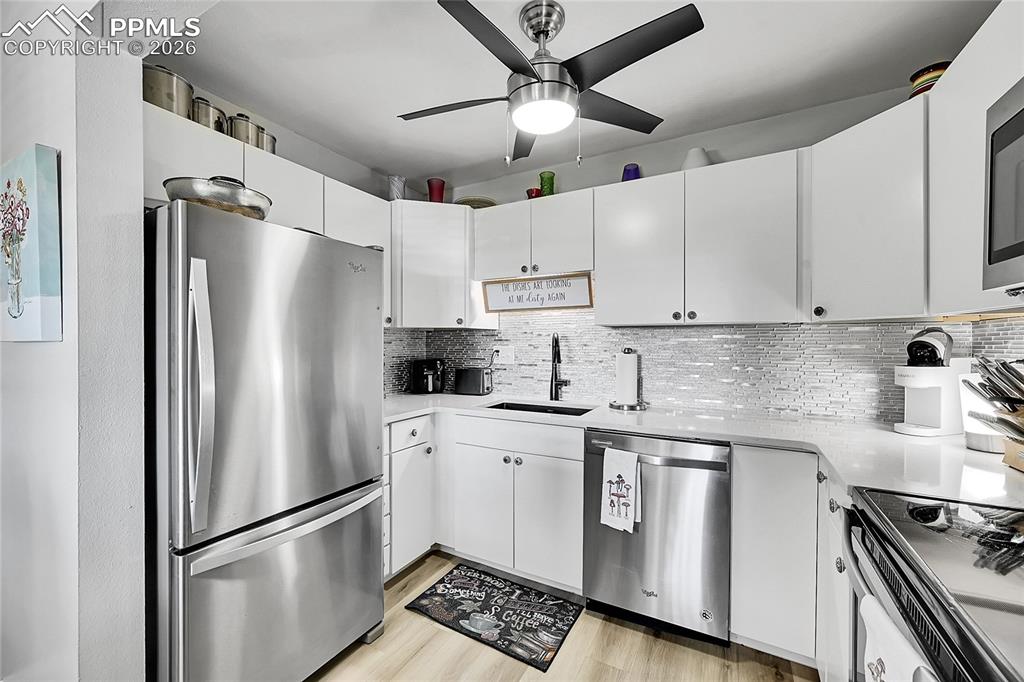 Image 7 of 42: Kitchen with sink, white cabinetry, light hardwood / wood-style floors, sta