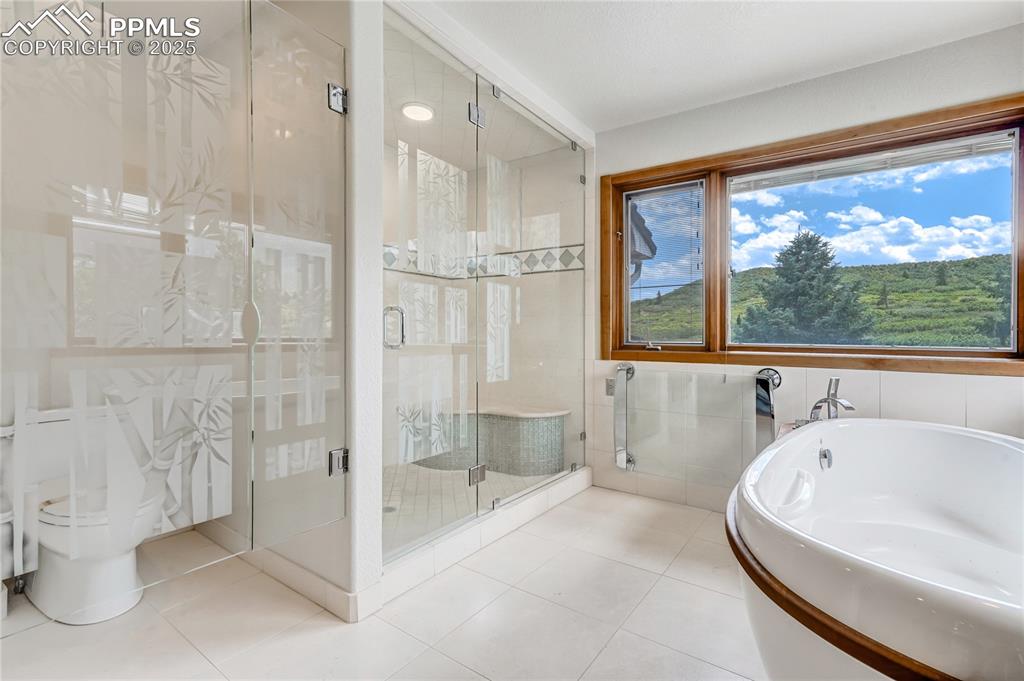 Image 20 of 50: Bathroom with a shower stall, a bath, tile walls, and tile patterned floors