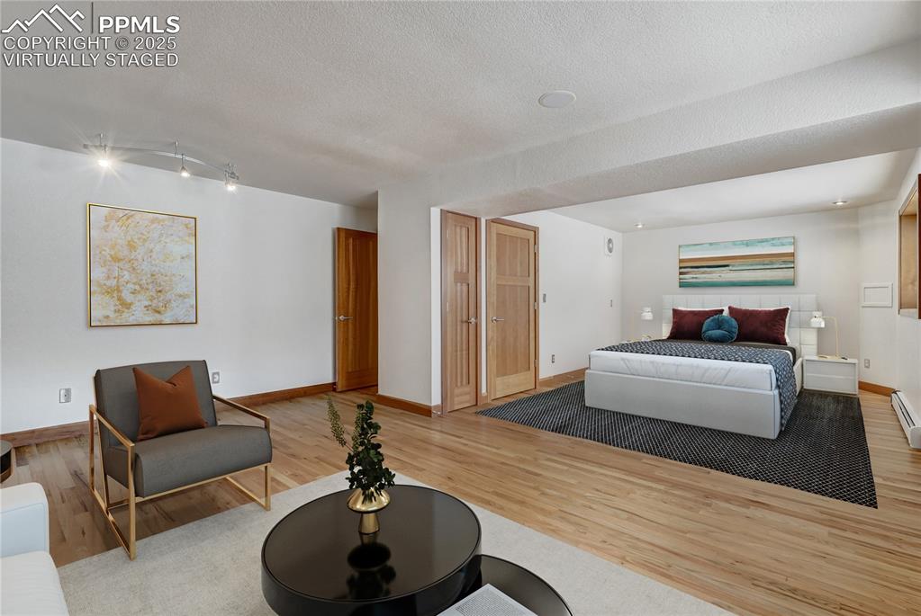 Image 28 of 50: Bedroom featuring light wood-style floors and a textured ceiling, virtually