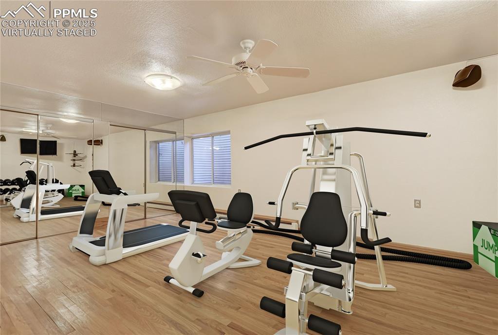 Image 30 of 50: Workout area featuring a textured ceiling, light wood-type flooring, and ce