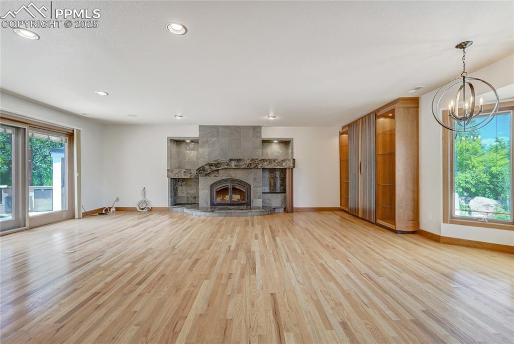 Image 7 of 50: Unfurnished living room with a tiled fireplace, light wood-style flooring, 