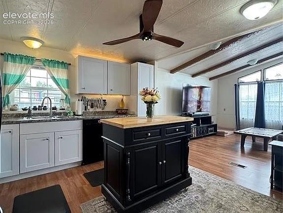 Image 11 of 34: Kitchen with a central black island featuring a butcher block countertop, w