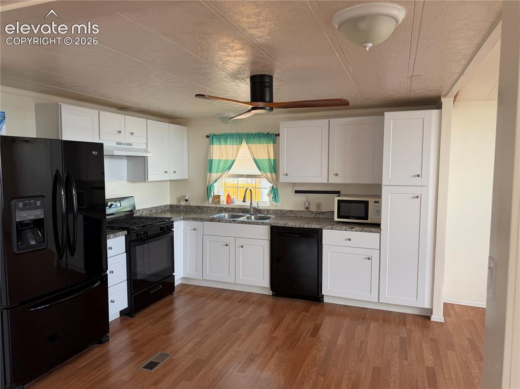 Image 14 of 34: Kitchen featuring wood-finish flooring, white cabinetry, dark countertops, 