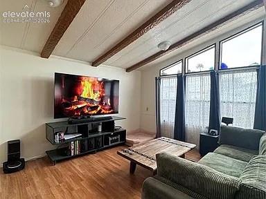 Image 15 of 34: Living area featuring wood-finish flooring, exposed ceiling beams, and a va