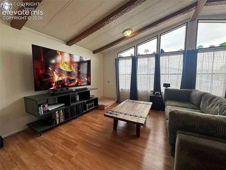 Image 17 of 34: Living area featuring wood-finish flooring, a vaulted ceiling with exposed 