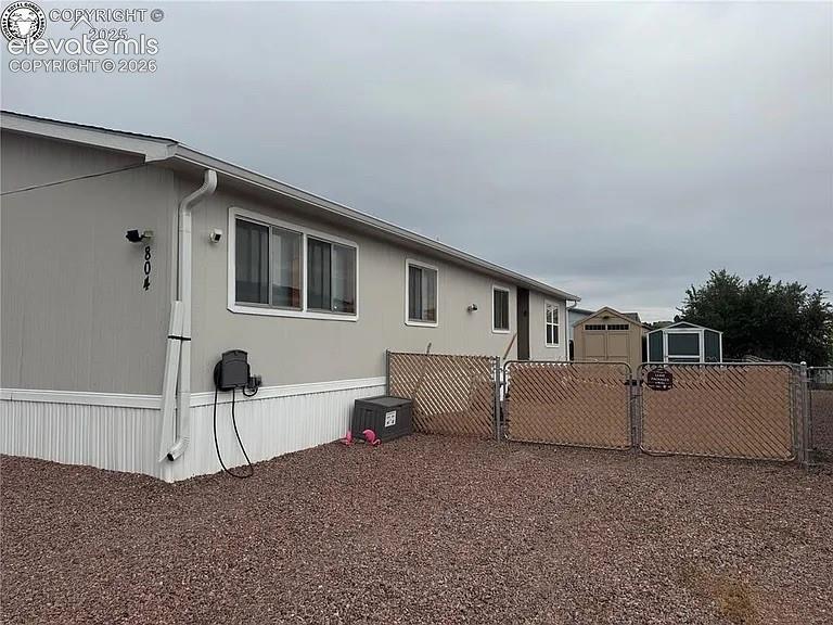 Image 2 of 34: Front of Home with gated area and two storage sheds