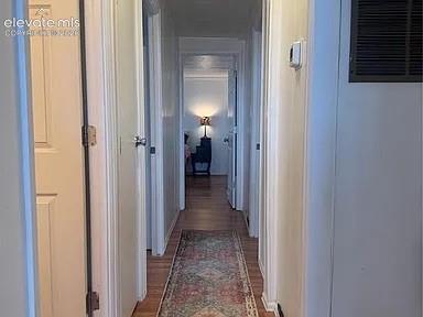 Image 21 of 34: Hallway featuring wood-finish flooring, white paneled doors, and a neutral 