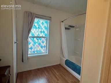 Image 26 of 34: Bathroom featuring a patterned window, wood-finish flooring, and a white sh