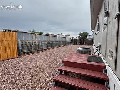 Image 29 of 34: Rear exterior featuring a red-stained wood deck, gravel landscaping, and a 